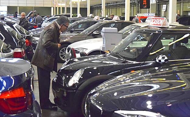 Un hombre observa un vehículo de ocasión en una feria de automoción.