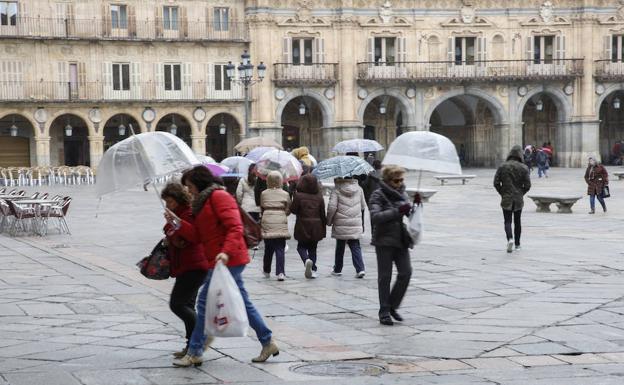 Varias personas se protegen de la lluvia en la Plaza Mayor de Salamanca, ayer.