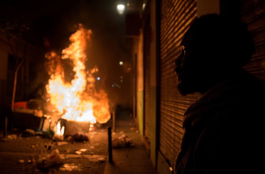 Un grupo de más de medio centenar de personas han quemado contenedores y causado desperfectos en el mobiliario urbano en el madrileño barrio de Lavapiés tras la muerte este jueves de un mantero de 35 años y origen subsahariano a causa de una parada cardiorrespiratoria.