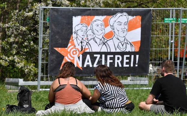 Asistentes a la contraprotesta frente a un cartel de 'Libre de nazis' justo al festival del cumpleaños de Hitler. 