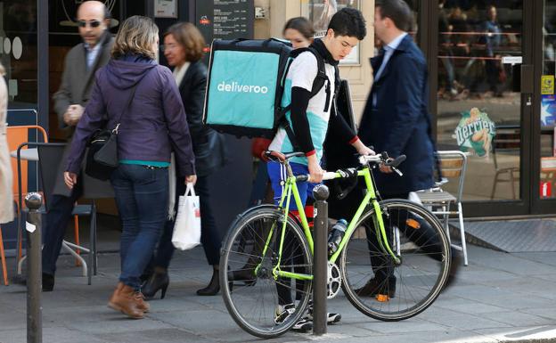 Un joven repartidor aparca su bici para entregar un pedido.