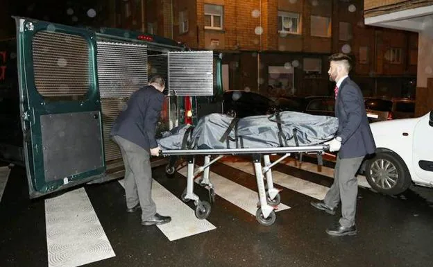 Los servicios funerarios introducen el cadáver de uno de los octogenarios fallecidos en el furgón para su traslado al Instituto de Medicina Legal, en Oviedo. 