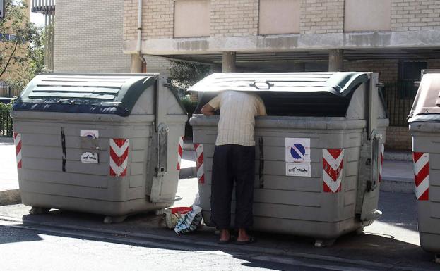 Una persona busca comida en un contenedor de basura del barrio vallisoletano de Huerta del Rey.