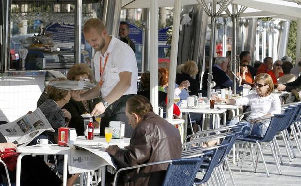 Un camarero sirve bebidas en una terraza en Alicante.