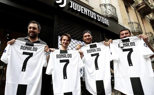 Aficionados de la Juventus posan con la camiseta de Cristiano Ronaldo. 