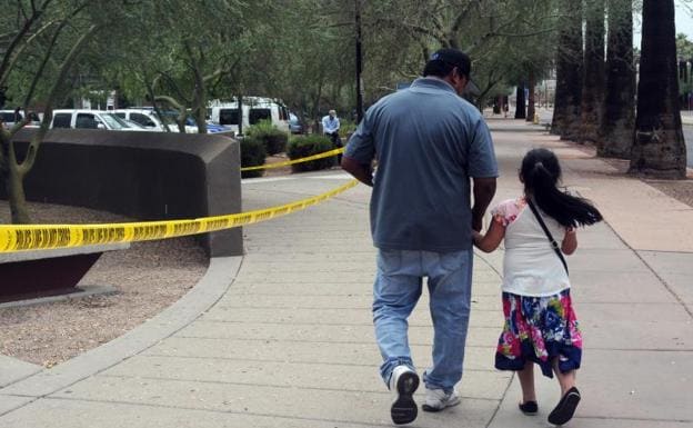 Un hombre camina junto a su hija tras salir de una cita en la Oficina de Control de Inmigración y Aduanas en Phoenix (Arizona).