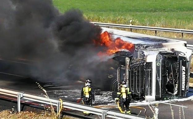 Los bomberos tratan de apagar el fuego que se originó en la cabina.