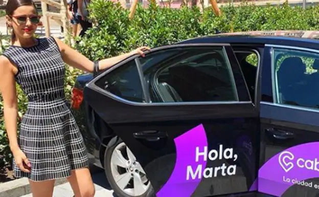 Marta Torné abre la puerta de un coche de la empresa Cabify. 