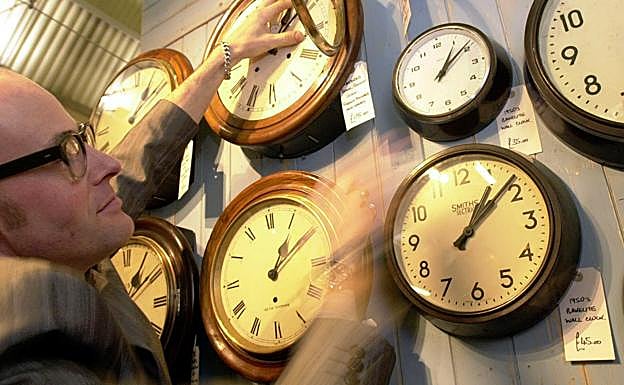 Un restaurador cambia de hora los relojes de su tienda de Londres.