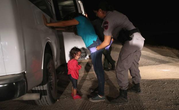 Una migrante y su hija de dos años son detenidos tras cruzar la frontera entre México y EE UU.