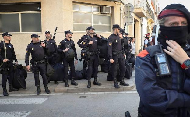 Un mosso hace guardia frente a policías nacionales.