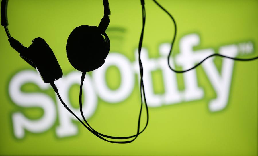 Auriculares frente al logotipo de Spotify, servicio de música en 'streaming'.