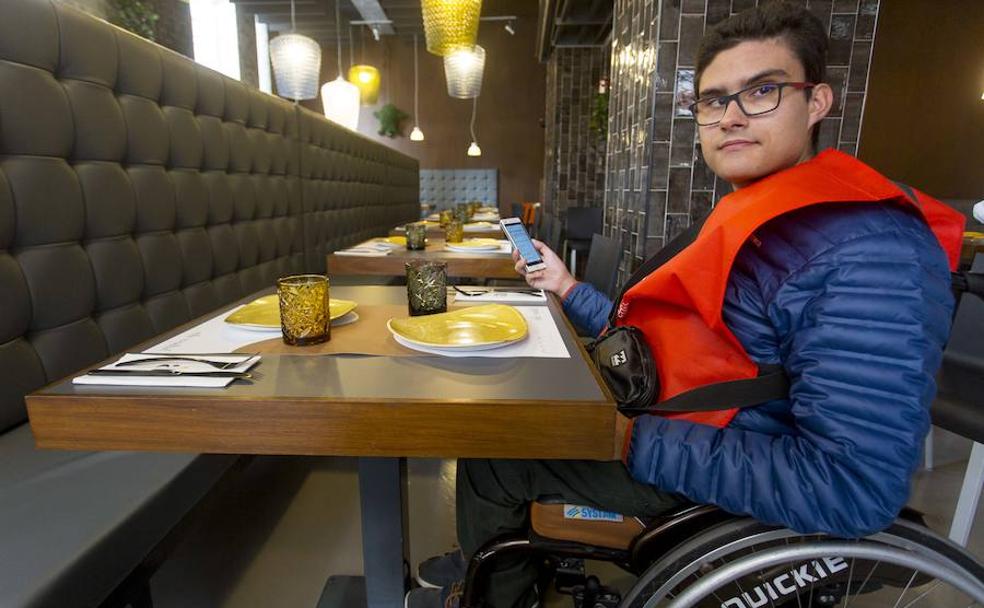 Mario Palenzuela acerca su silla de ruedas a la mesa del restaurante.