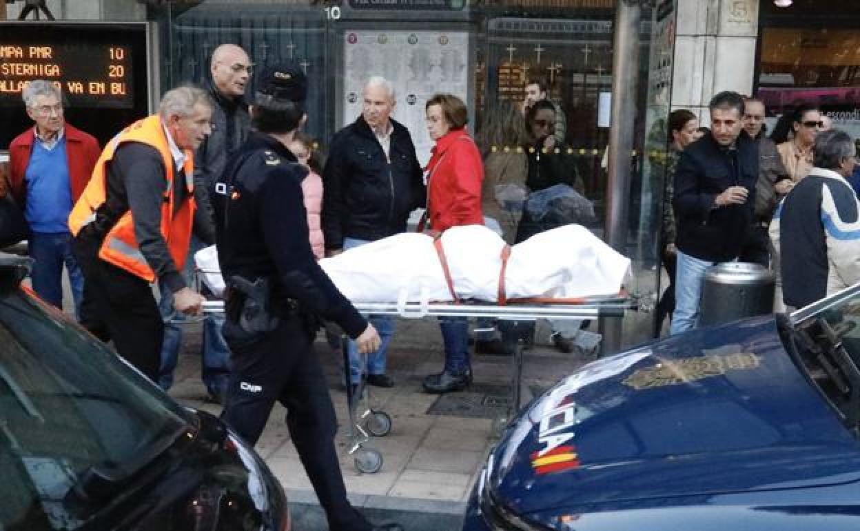 Agentes de Policía junto a operarios del servicio forense trasladan el cadáver de la mujer en la Plaza Circular de Valladolid.