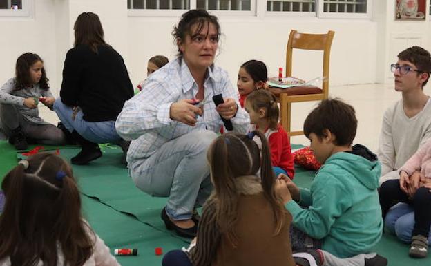 Varios niños, realizando manualidades bajo la supervisión de una monitora.