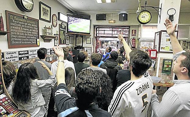 Clientes de un bar ven un partido de fútbol por televisión. 