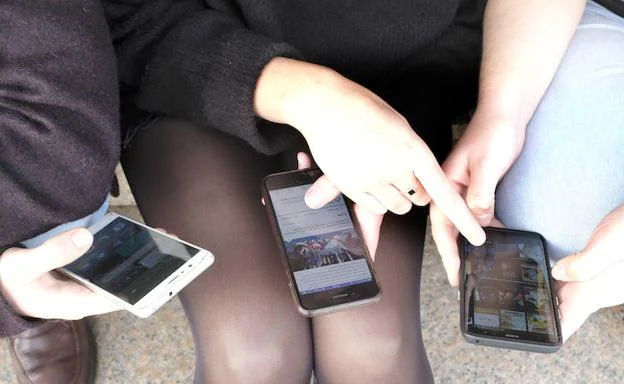 Varios adolescentes, con sus teléfonos móviles. 