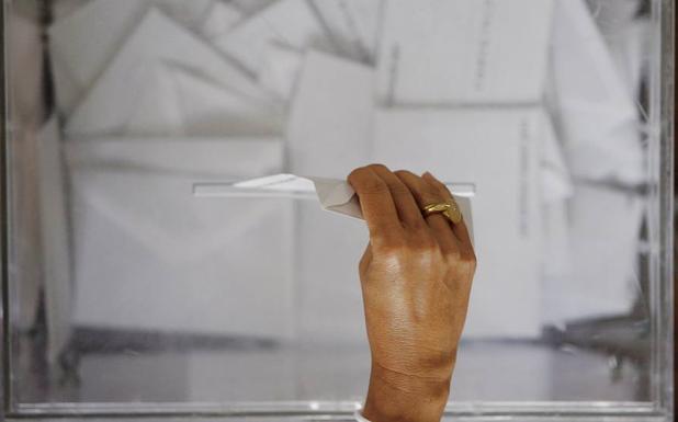Una mujer deposita su voto en una urna.