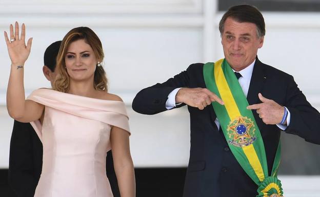 Bolsonaro (d) se señala la banda recibida como nuevo presidente junto a su mujer. 