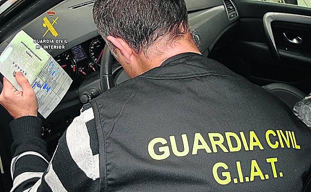 Un guardia civil del GIAT comprueba las tarjetas de inspección técnica de los vehículos. 