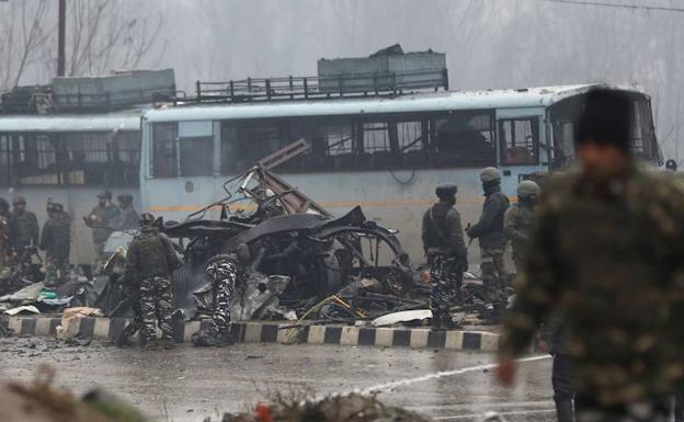 Varios policías observan el lugar del ataque con bomba contra el vehículo en el que viajaban en una carretera del distrito de Pulwama de la Cachemira india. 