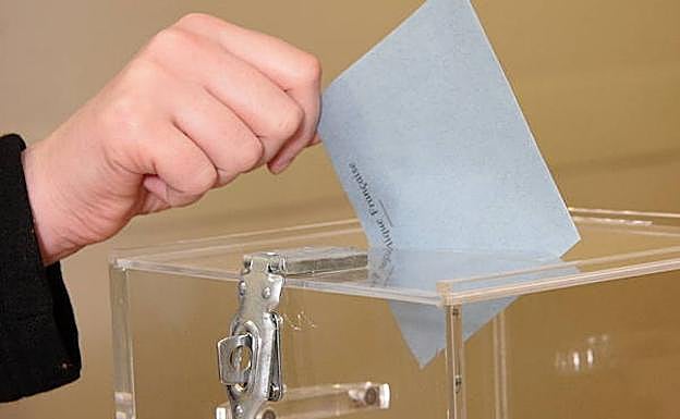 Un hombre deposita su voto en una urna.