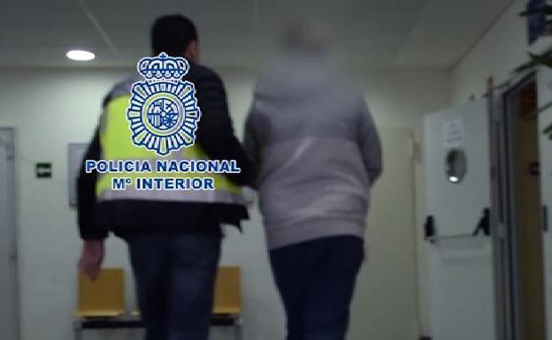 Un policía lleva esposado al detenido. 