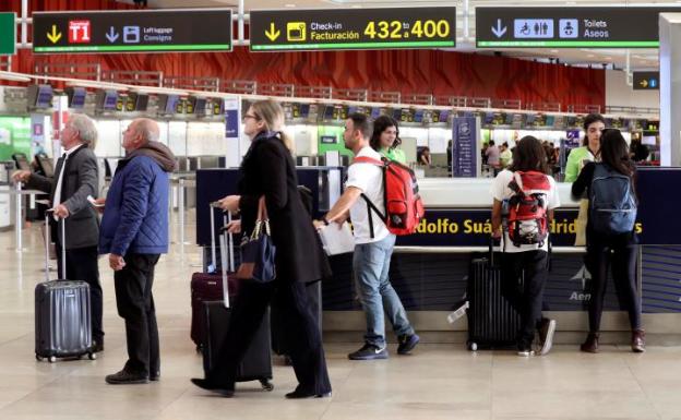 Varios pasajeros, este viernes, ante uno de los mostradores de información del aeropuerto de Madrid-Barajas.