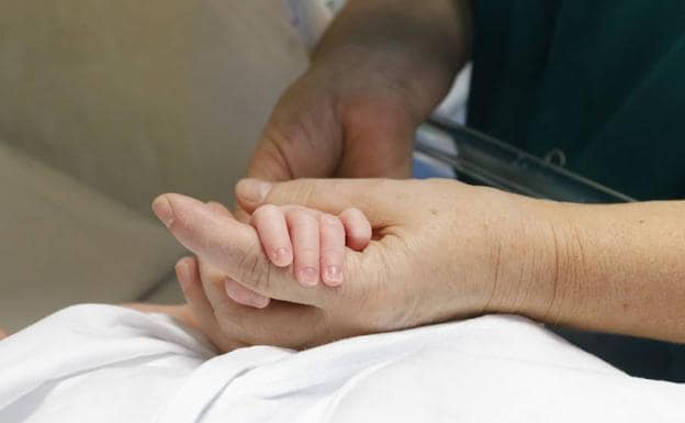Una mujer sostiene la mano de un recién nacido. 