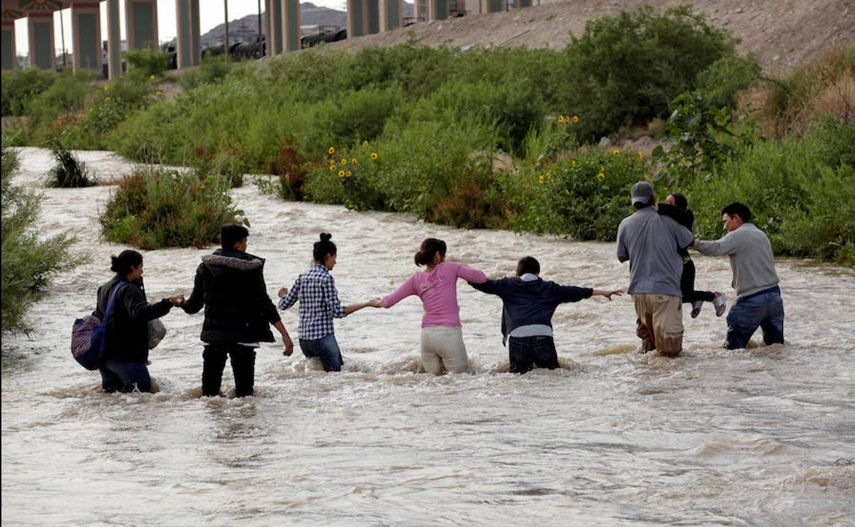 Inmigrantes centroamericanos se ayudan para cruzar el río Bravo a su paso por la ciudad mexicana de El Paso.