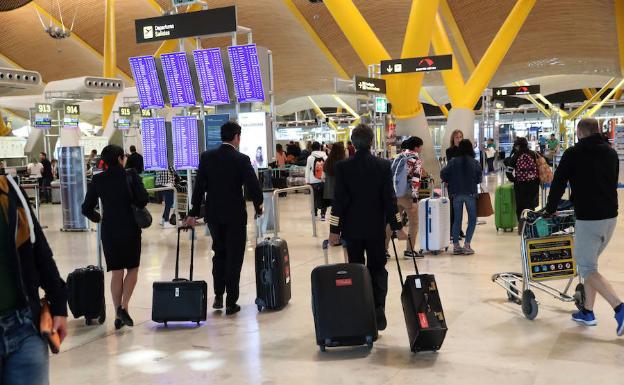 Varios viajeros en el aeropuerto internacional de Madrid-Barajas se dirigen hacia sus vuelos.