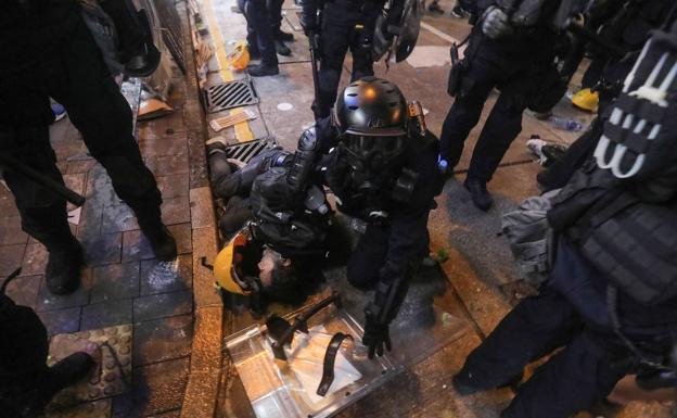 Imagen principal - Manifestantes detenidos por la policía en Hong Kong.