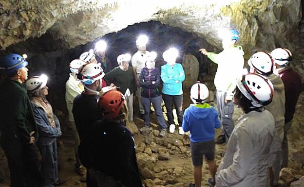 Un grupo de turistas visita una cueva. 