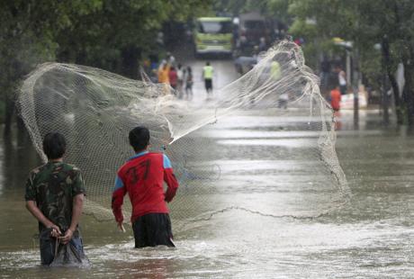 Imagen - Varios lugareños pescan en una calle inundada de Yakarta el 13 de enero de 2014. EFE