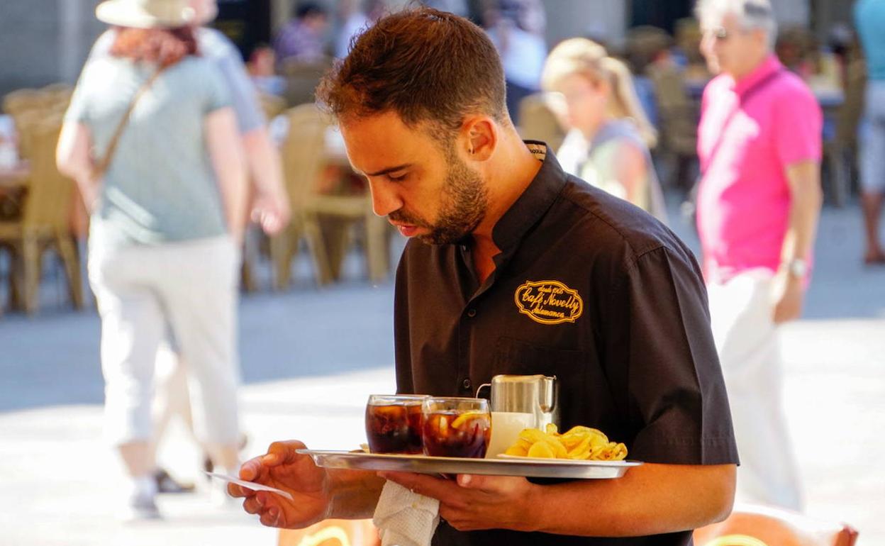 Un camarero porta una bandeja en un bar de la comunidad.