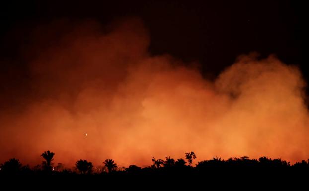 El fuego ilumina el cielo nocturno de Humaita mientras deja un paisaje carbonizado en Iranduba, dos parajes de la selva del Amazonas.