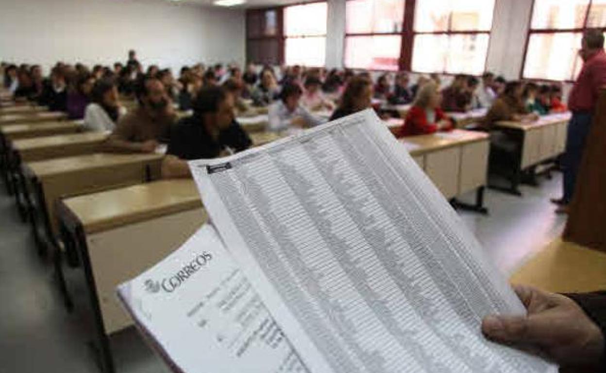 Un grupo de personas, examinándose a las oposiciones de Correos. 