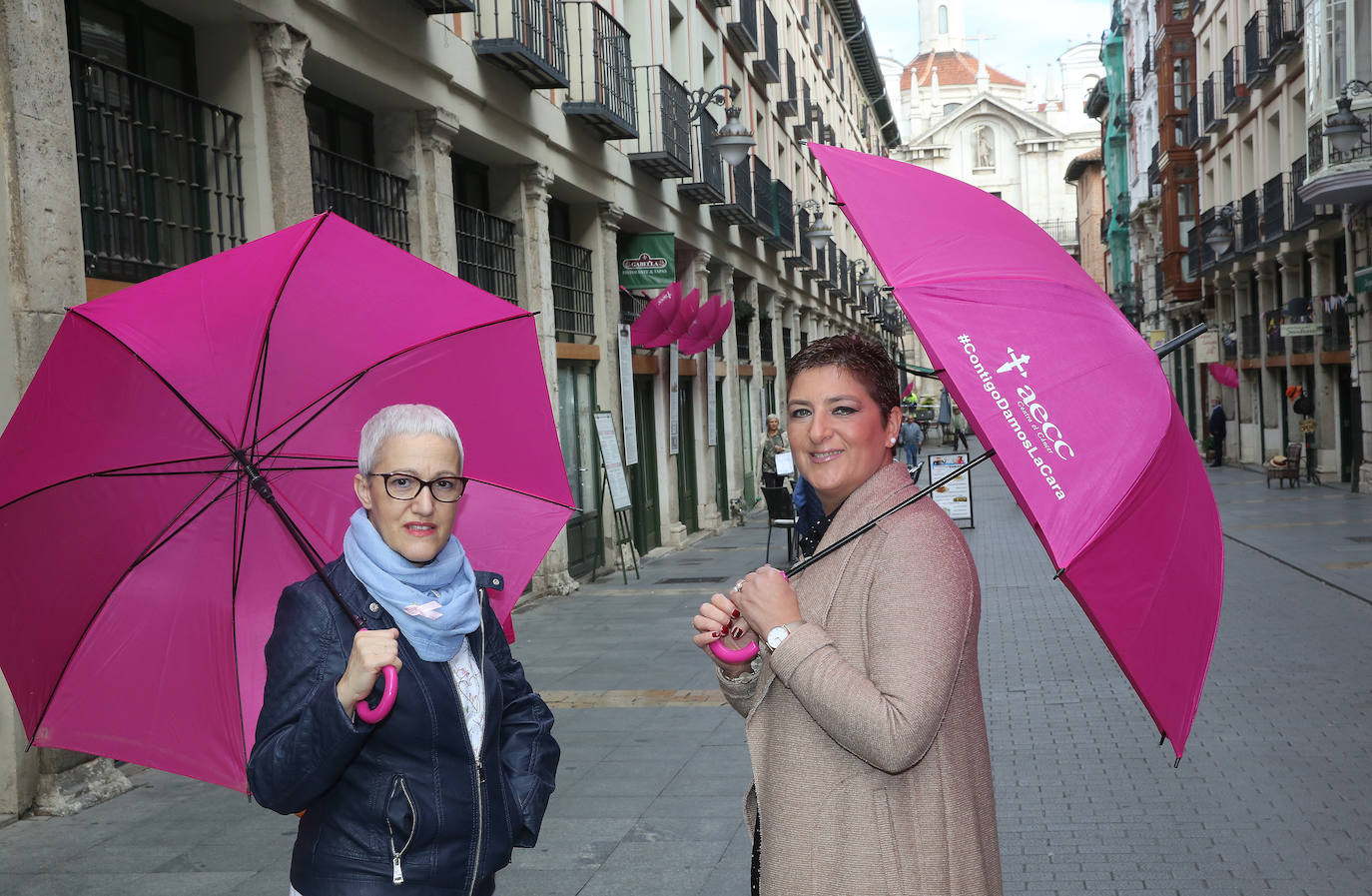 Rosa Fuentes y Mónica Fernández, con los paraguas de la AECC, ayer en la calle Platerías.