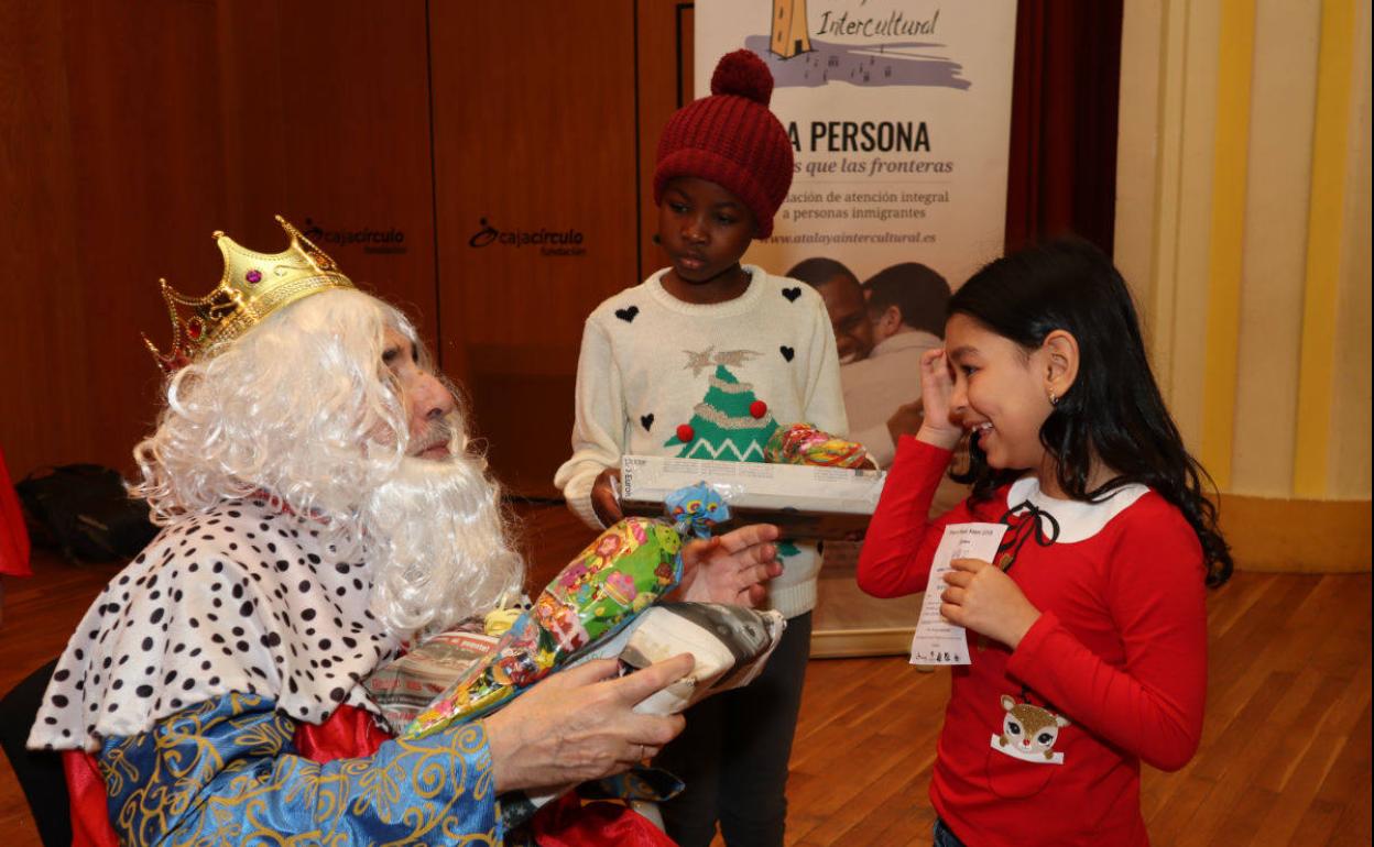 Melchor entrega varios regalos a dos niños.