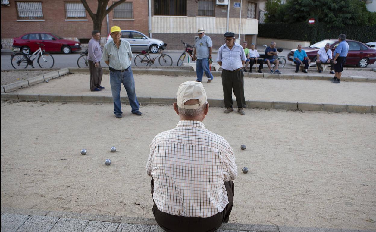 Un grupo de jubilados juega a la petanca en el parque.