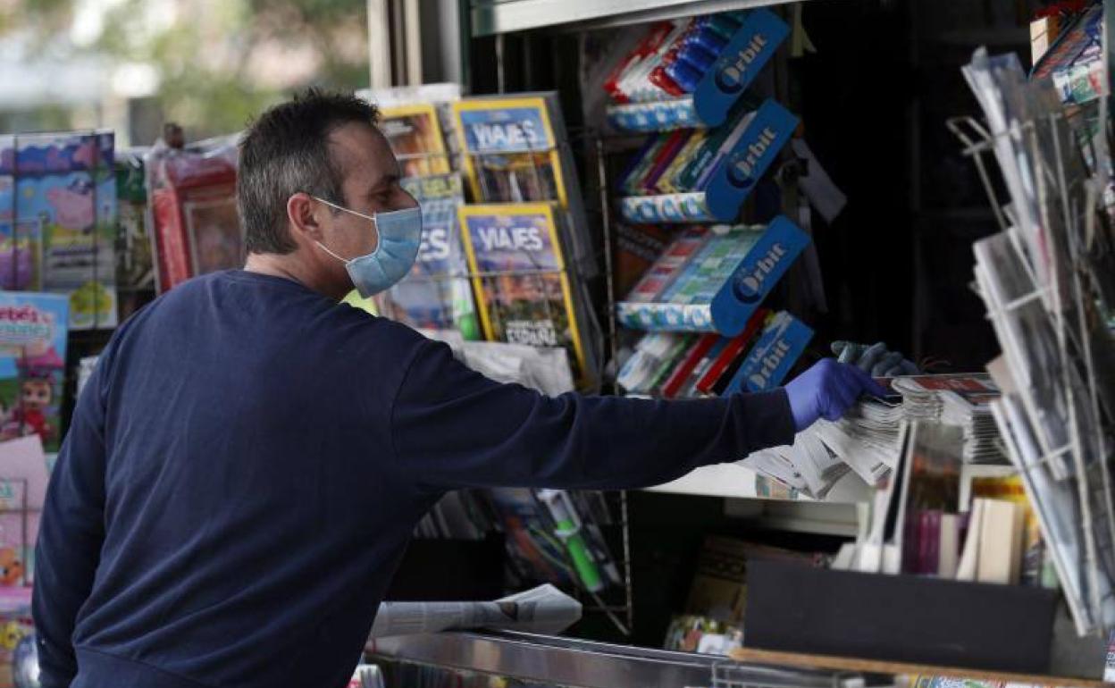 Un lector protegido con mascarilla compra periódicos este domingo en Bilbao.