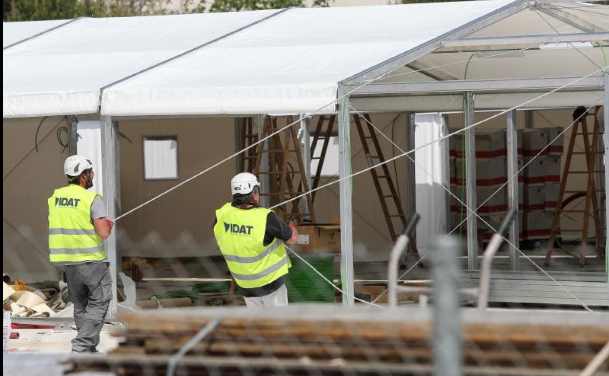 Dos trabajadores preparan una carpa en el hospital de campaña instalado junto al Hospital La Fe de Valencia.