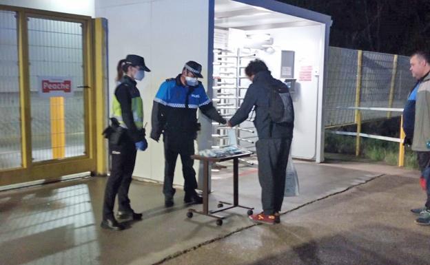 La Policía Local entrega mascarillas en la entrada de la factoría de Leche Pascual. 