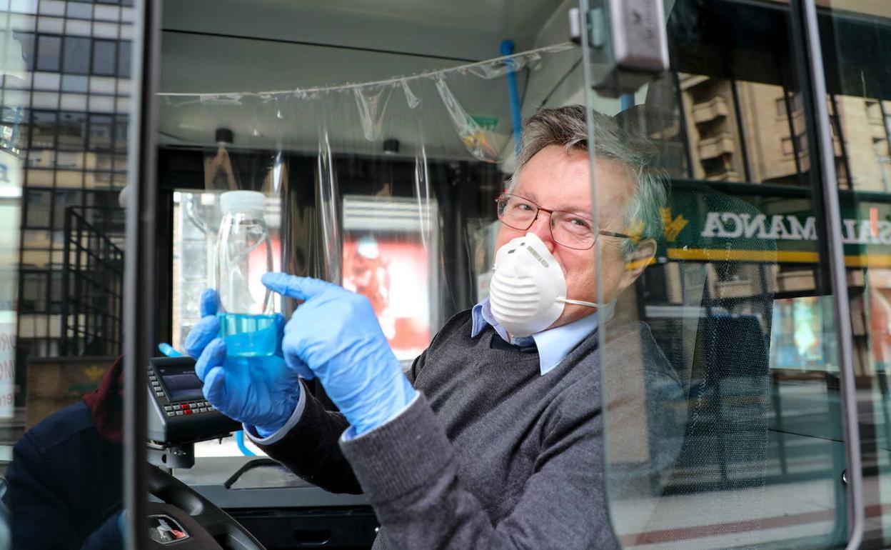 Un conductor de autobús con mascarilla, guantes y gel. 