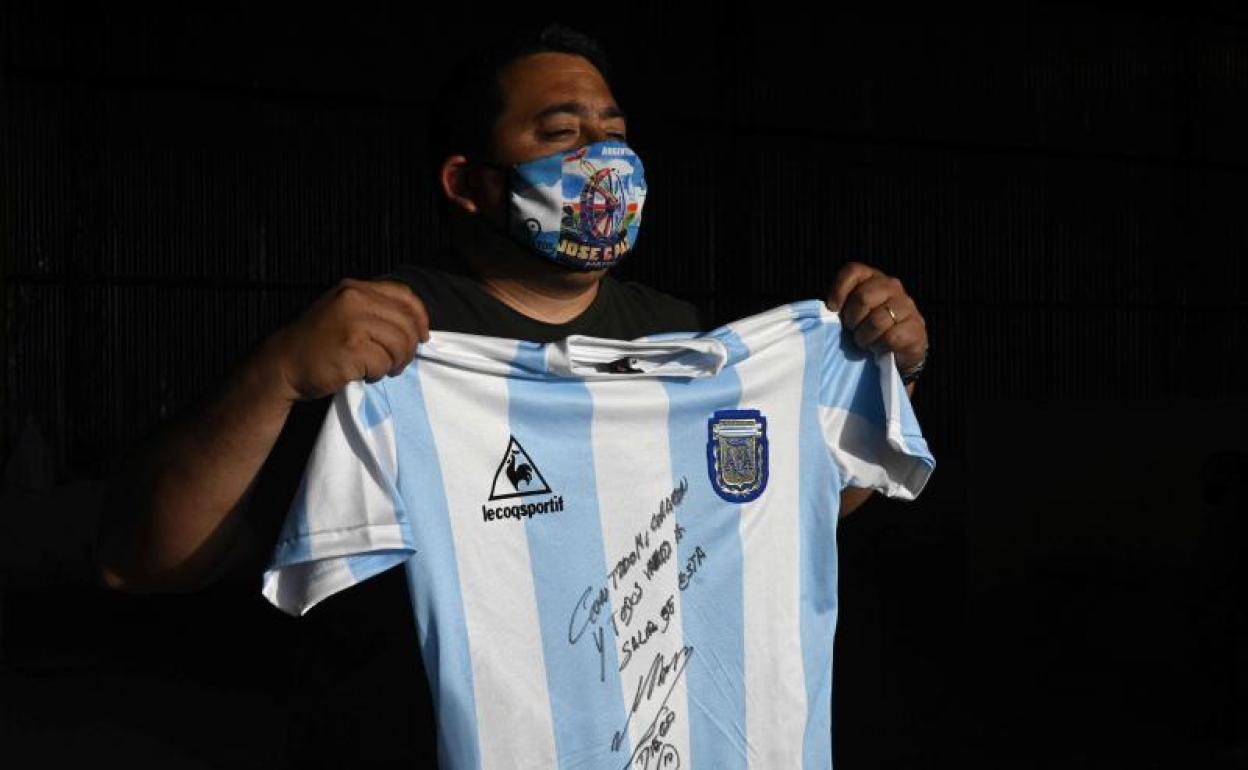 Un ciudadano posa con la camiseta firmada y donada por Maradona, réplica de la que utilizó Argentina en el Mundial'86. 