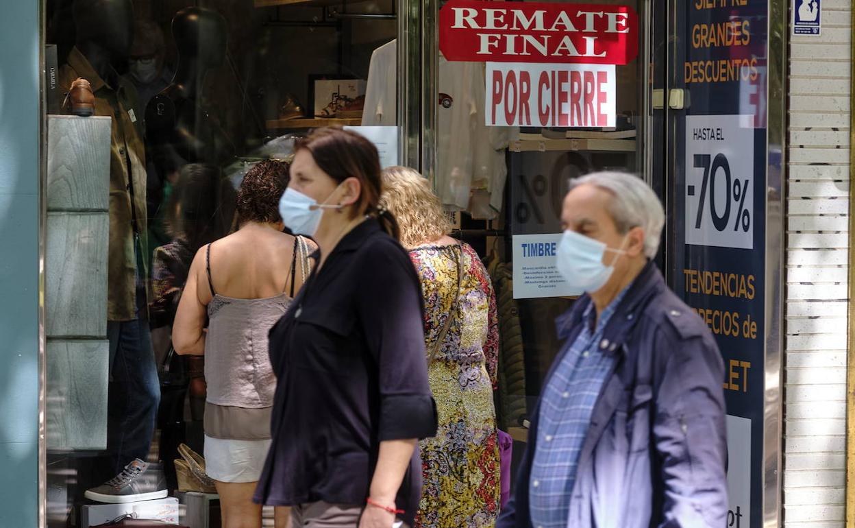 Vallisoletanos pasean delante de un comercio en liquidación.