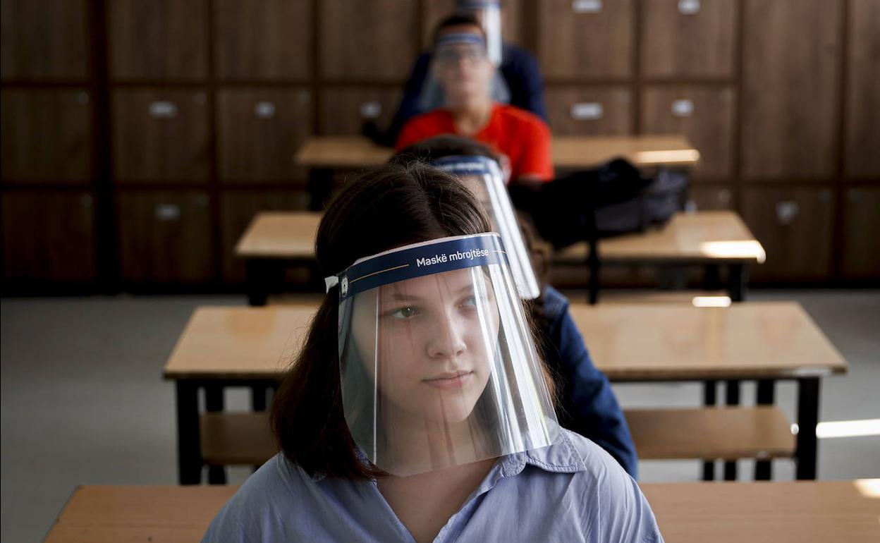 Alumnos de secundaria en un centro educativo de Pristina, en Serbia, asisten a clase con una pantalla protectora. 