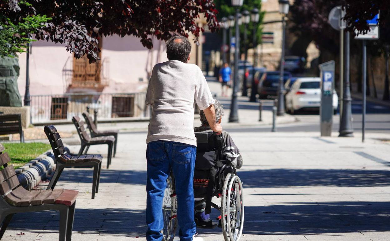 Un hombre empuja la silla de ruedas de una mujer en Salamanca. 