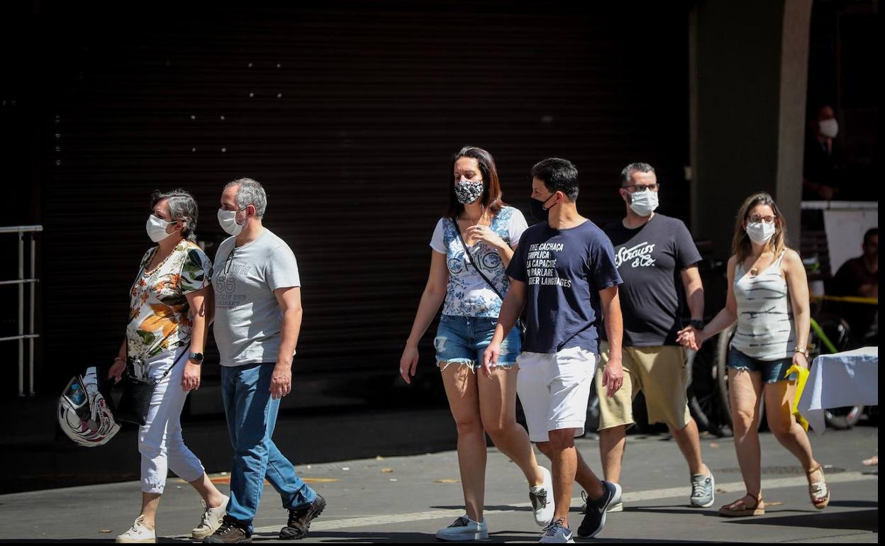 Varias personas con mascarilla pasean por la calle.