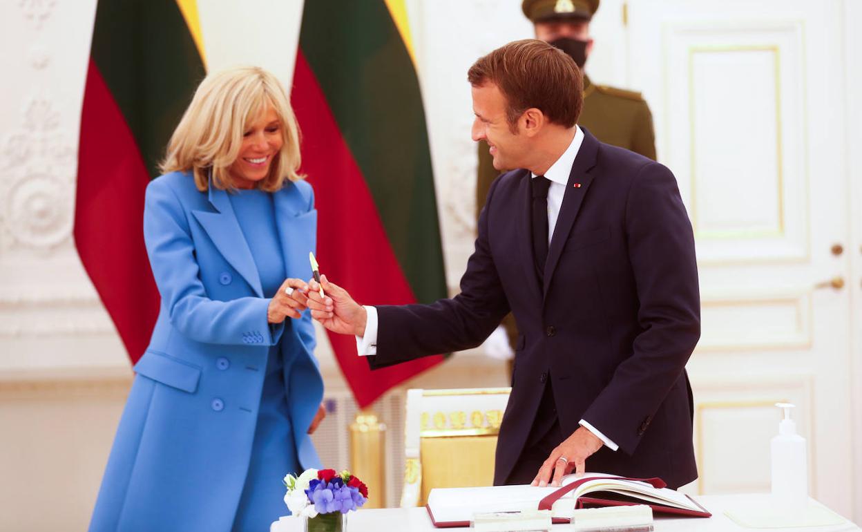 Macron entrega el bolígrafo a su mujer, Brigitte, para que firme en el libro de visitantes de honor a su llegada a Lituania. 